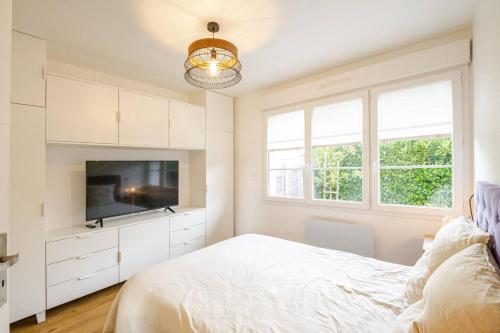 a white bedroom with a bed and a tv at Charmante maison avec piscine in Beaussais sur Mer