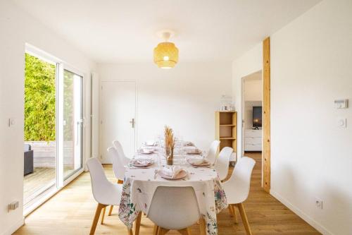 a dining room with a table and white chairs at Charmante maison avec piscine in Beaussais sur Mer