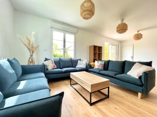 a living room with blue couches and a coffee table at Charmante maison avec piscine in Beaussais sur Mer
