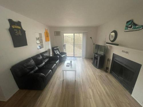 a living room with a black leather couch and a fireplace at Close to TRU, Sun Peak, shopping in Kamloops