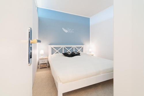 a bedroom with a white bed and a blue wall at Panoramic App A06-6 in Sierksdorf