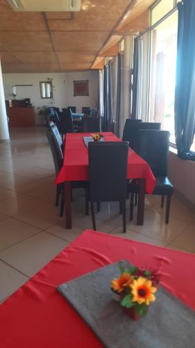 a restaurant with red tables and chairs with flowers on them at Ochsenwagen Pension Hotel in Rehoboth