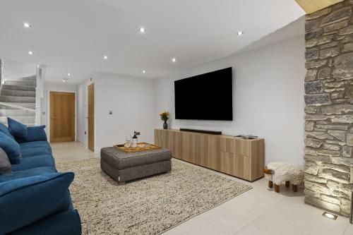 a living room with a blue couch and a tv at The Old School House - A Superb Newly Converted Barn with Hot Tub Sleeping 8 guests in Carmarthen
