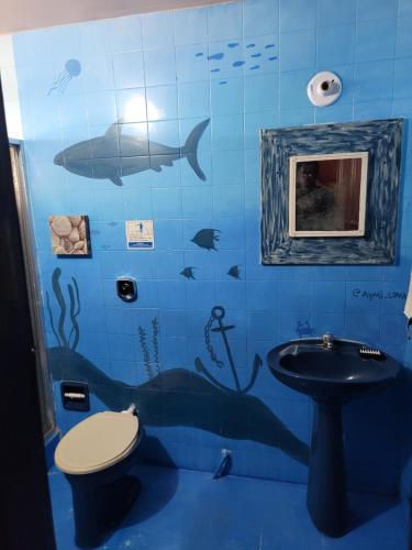 a blue tiled bathroom with a toilet and a sink at Saqua Beach Hostel in Saquarema