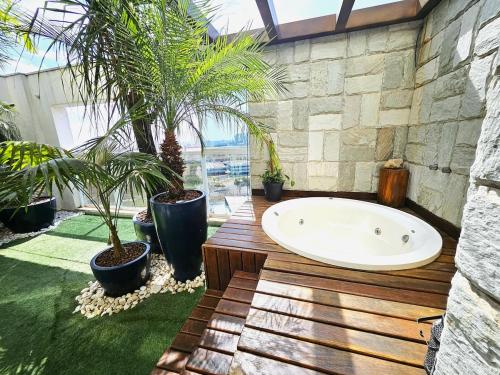 SPOT · Cobertura c/hidro em Aguas Claras, SPOT Apartments في برازيليا: حوض استحمام في غرفة مع نباتات الفخار
