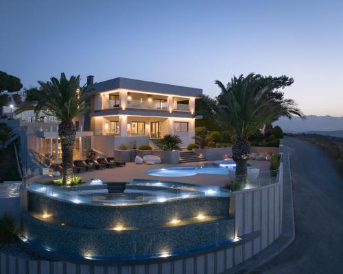 a house with a swimming pool at night with palm trees at Villa Kalliston in Rethymno Town