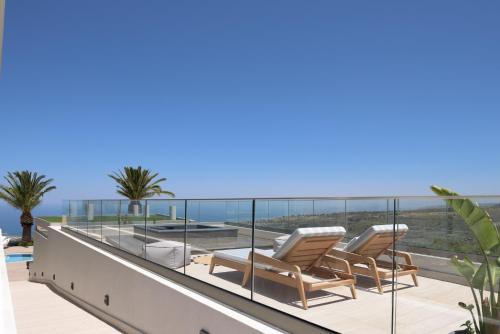 a balcony with two lounge chairs and the ocean at Villa Kalliston in Rethymno Town