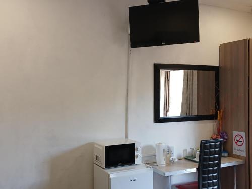 a room with a desk with a microwave and a television at Kadichueni Guest House in Zeerust