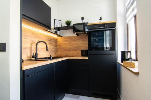 a kitchen with black cabinets and a sink at StayFine - smartes Design Apartment am Uni Campus in Chemnitz