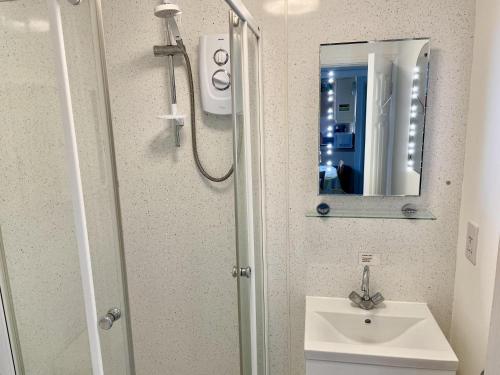 a bathroom with a sink and a shower with a mirror at 2 Bed Lodge - Sleeps 4 - Pets - Pool - Garden in Penzance