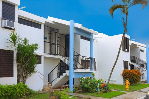 a white building with balconies and a palm tree at Villa Layka Beach House at Playas del Yunque in Rio Grande