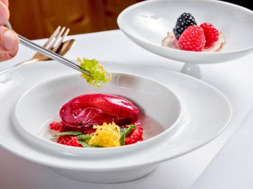a plate of food with fruit in a bowl on a table at Hotel Lamm in Heimbuchenthal