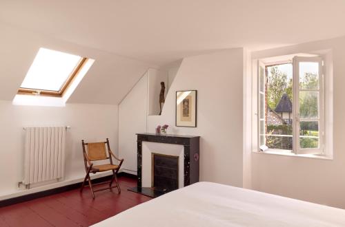 - une chambre avec un lit, une chaise et une cheminée dans l'établissement La maison de Crèvecoeur, à La Croix-Saint-Leufroy