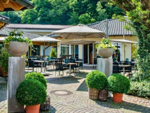 a patio with tables and chairs and umbrellas and plants at Hotel Lamm in Heimbuchenthal