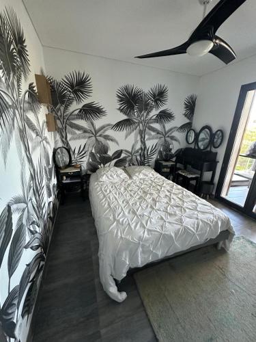 - une chambre avec un lit et des palmiers sur le mur dans l'établissement Villa luxe bord de mer, jardin, piscine, à Corbara