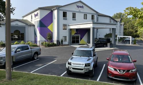 two cars parked in a parking lot in front of a building at Spark by Hilton Winston-Salem University in Winston-Salem