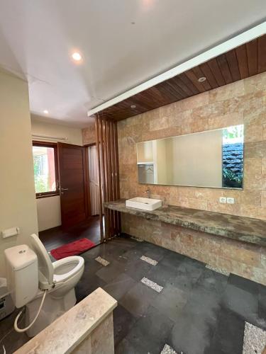 a bathroom with a toilet and a sink and a mirror at Riverside Villa Tanah Lot by Smart Digital in Munggu