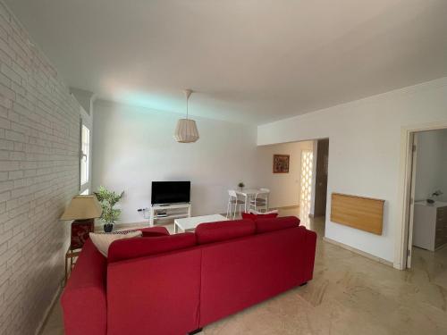 a living room with a red couch and a tv at Deluxe Ciudad Jardin - by Gestión Vacacional Canarias in Las Palmas de Gran Canaria