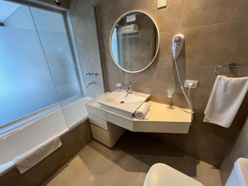 a bathroom with a sink and a mirror and a tub at Hotel Zentiva Pinamar in Pinamar
