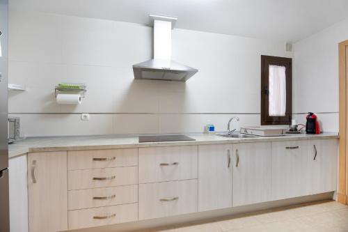 a kitchen with white cabinets and a sink and a mirror at Apartamento Costa De La Luz in Rota