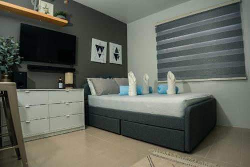 a bedroom with a bed with a dresser and a flat screen tv at KaribuBnb in Lapu Lapu City