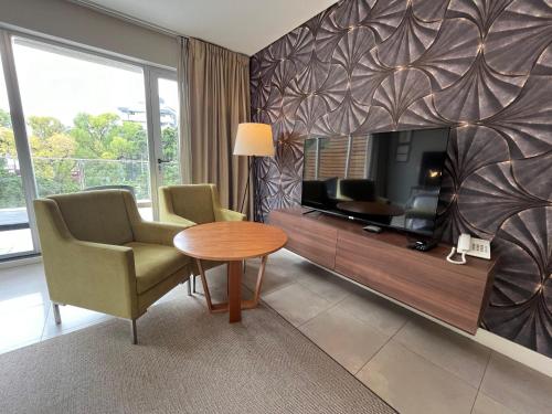 a living room with a tv and a table and chairs at Hotel Zentiva Pinamar in Pinamar