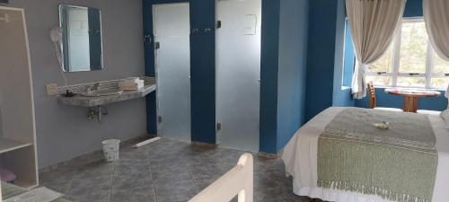 a blue room with a bed and a sink at Hotel - Pousada 3 Marias in São Pedro