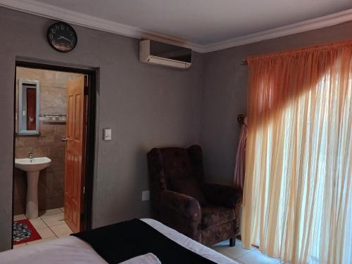 a bedroom with a bed and a chair and a sink at Kadichueni Guest House in Zeerust