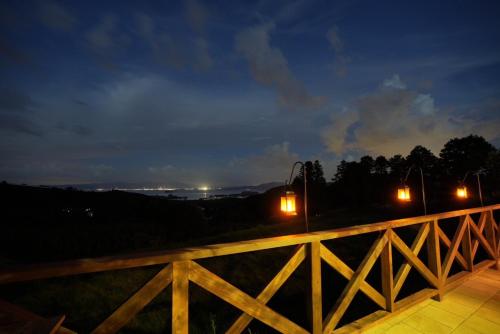 a balcony with lights on a fence at night at 長崎の丘に浮かぶ天空テラス Villa 森の魔女 ,Villa Forest Witch in Nagasaki