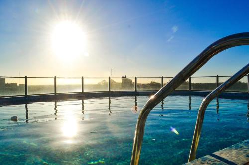 a swimming pool with the sun in the background at Hotel Zentiva Pinamar in Pinamar