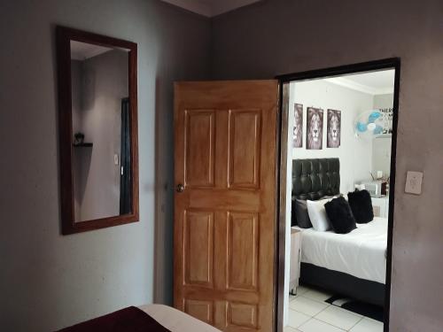 a room with a door and a bed with a mirror at Kadichueni Guest House in Zeerust