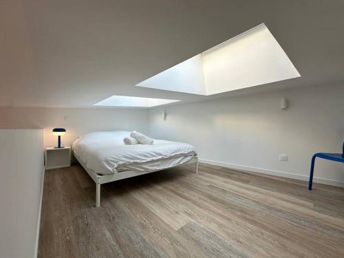 - une chambre blanche avec un lit et une lucarne dans l'établissement Libergier- Maisonnette cathédrale, à Reims