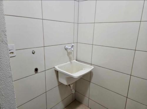 baño con lavabo blanco en la pared de azulejos en casa de temporada, en Goiânia