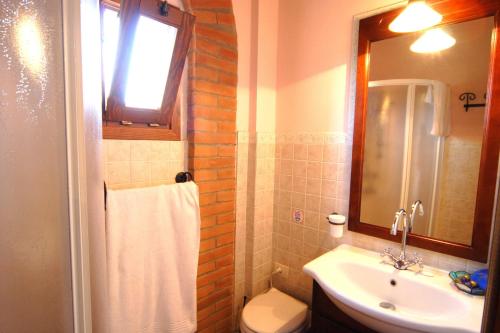 Un baño con lavabo, inodoro y espejo. en Villa Roseto Exclusive villa with swimming pool, en San Gimignano
