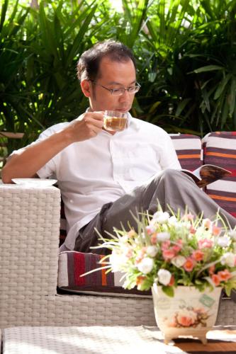 a man sitting in a chair drinking a glass of wine at Boonsiri Boutique Hotel in Si Sa Ket