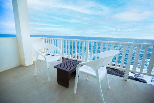 two chairs and a table on a balcony with the ocean at Hotel Zeilan Sunset Point in Unawatuna
