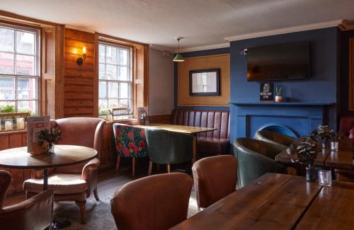 a restaurant with tables and chairs and a tv at The Bushel by Greene King Inns in Bury Saint Edmunds