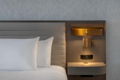 a hotel room with a bed with a white pillow and a nightstand at Hampton Inn By Hilton Winnipeg Downtown in Winnipeg