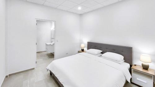 a white bedroom with a large bed with two pillows at Bocobay Penthouse 4BR 4BA with Rooftop Pool in Oranjestad