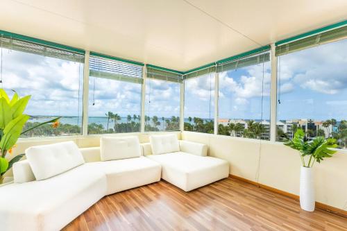 - un salon avec un canapé blanc et de grandes fenêtres dans l'établissement Bocobay Penthouse 4BR 4BA with Rooftop Pool, à Oranjestad