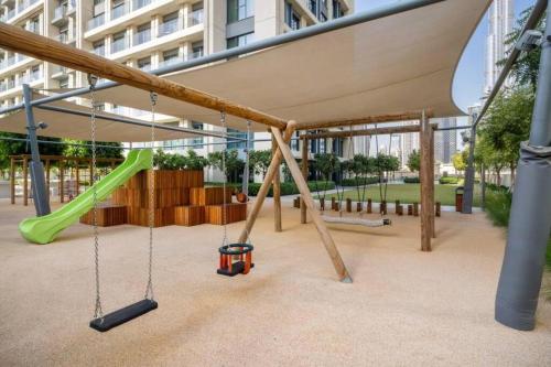 a playground with swings and a slide at 5 Minute Walk to The Fountains! Full Burj Khalifa View! 5-star Pool & Gym! in Dubai