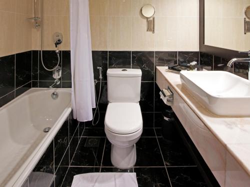 a bathroom with a toilet and a sink and a tub at Impiana Hotel Ipoh in Ipoh