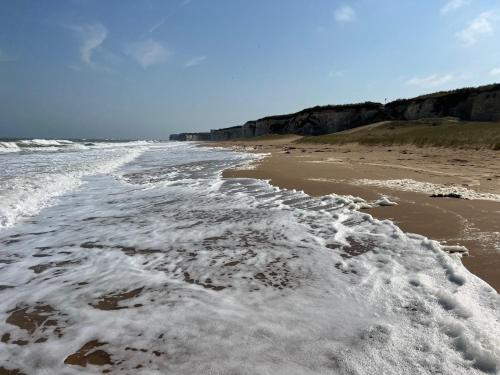 a beach with foamy water and footprints in the sand at Seafront BnB at Botany in Kent