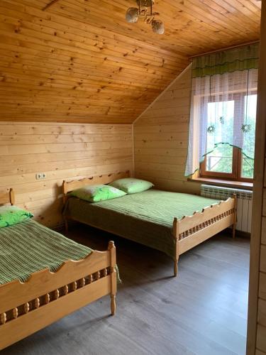 two beds in a log cabin with a window at Аура Карпат in Slavske