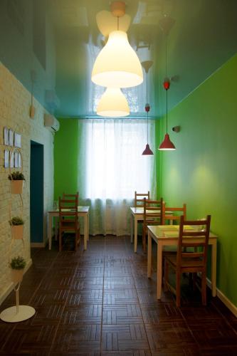 a restaurant with green walls and wooden tables and chairs at Mini-Hotel Spi Zdes in Khabarovsk