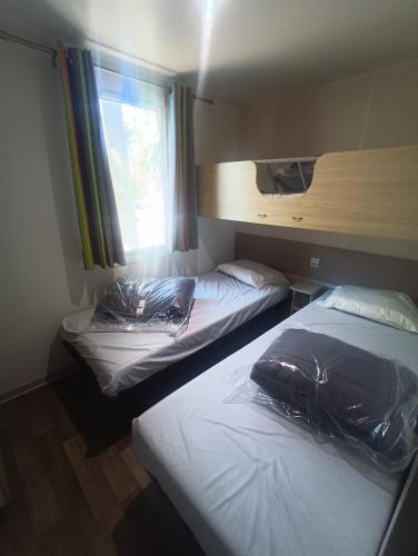deux lits dans une chambre avec une fenêtre dans l'établissement Mobile-home camping 7 fonts AGDE, à Agde
