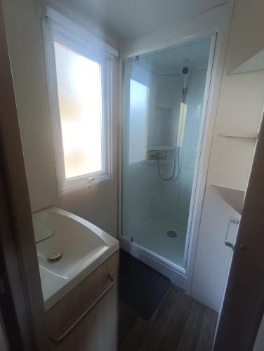 une salle de bain blanche avec une douche et un lavabo dans l'établissement Mobile-home camping 7 fonts AGDE, à Agde