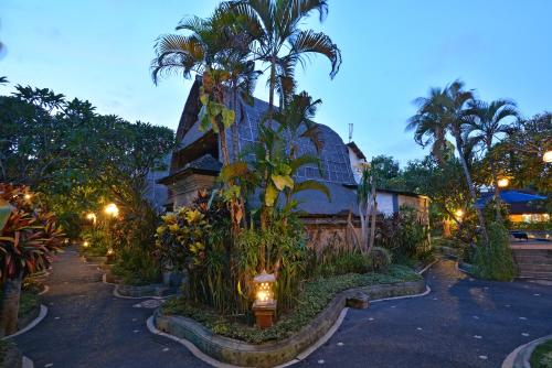 a house with palm trees and lights in front of it at Puri Dewa Bharata Hotel & Villas in Legian