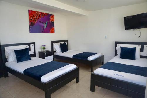 a room with two beds and a flat screen tv at Finca Hotel La Molienda Quindiana in Montenegro