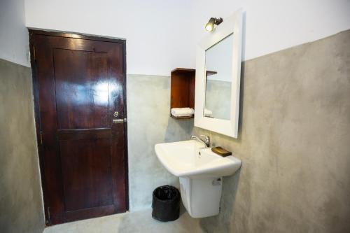 a bathroom with a sink and a wooden door at Hotel Zeilan Sunset Point in Unawatuna